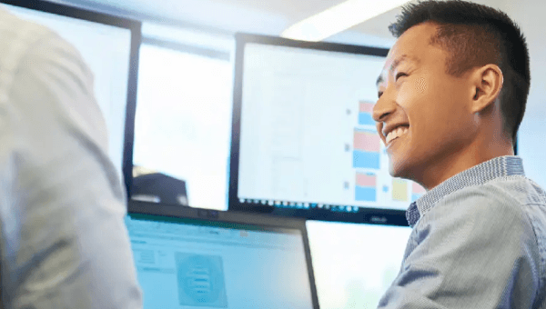 Image of man in office smiling in front of computer screen