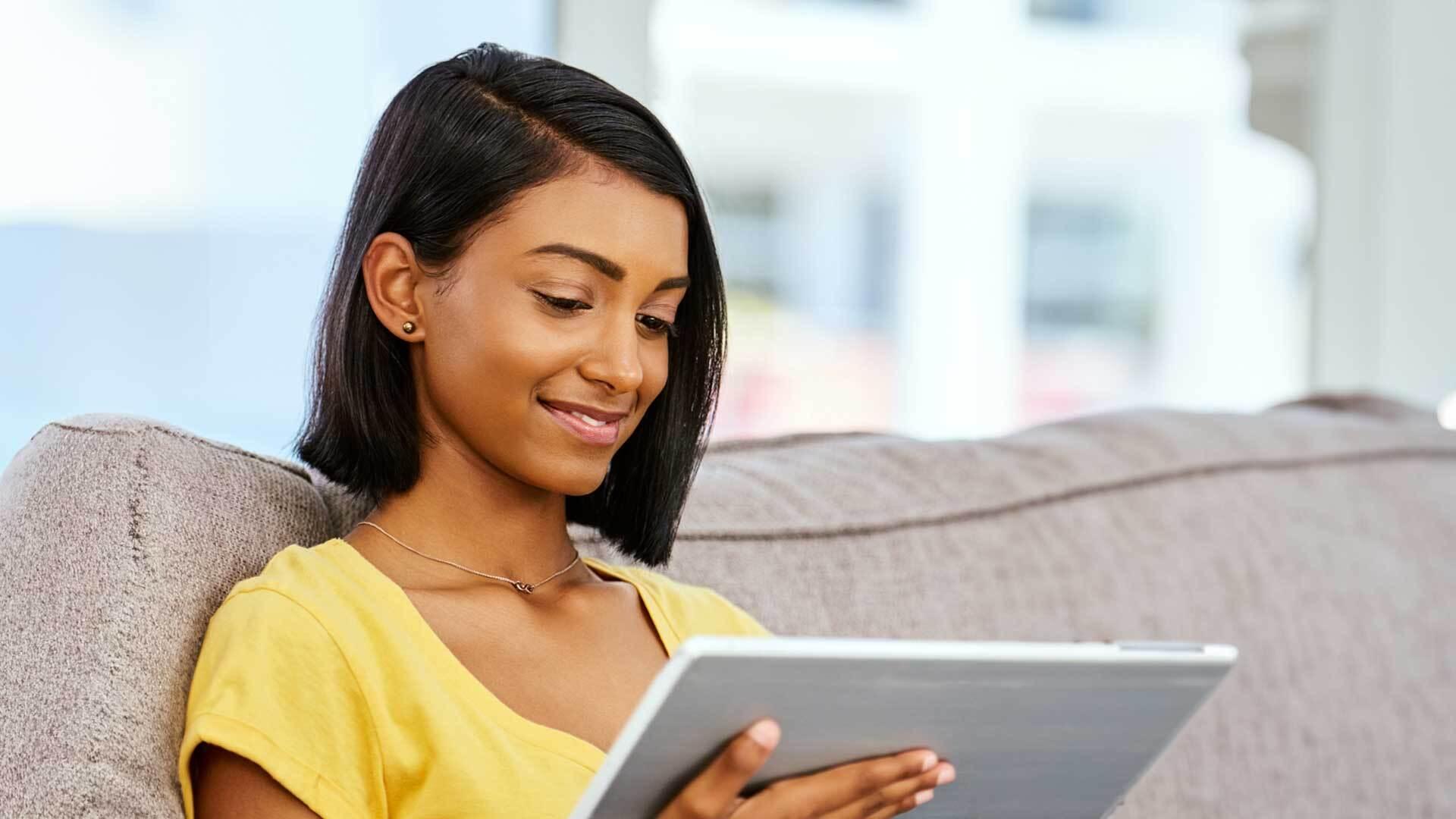 A sitting woman smiles at her tablet